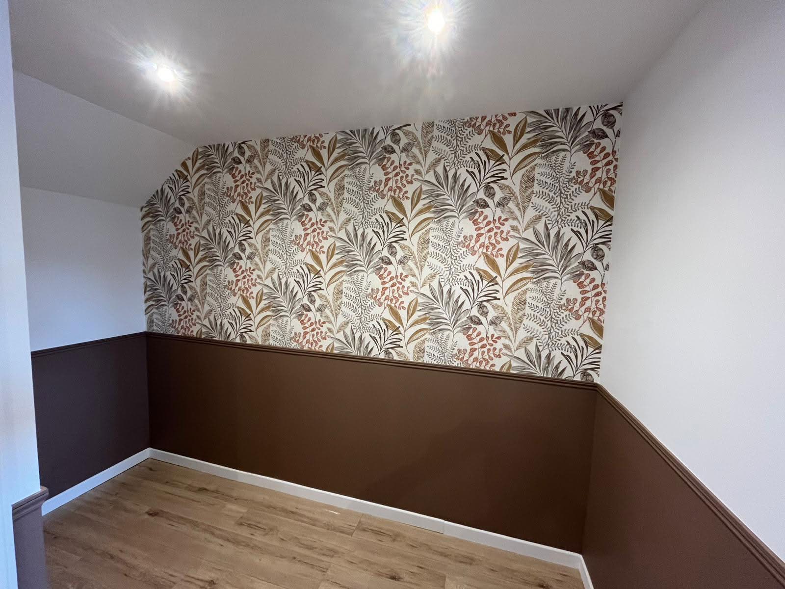 Chambre rénovée avec papier peint à motifs végétaux et soubassement marron
