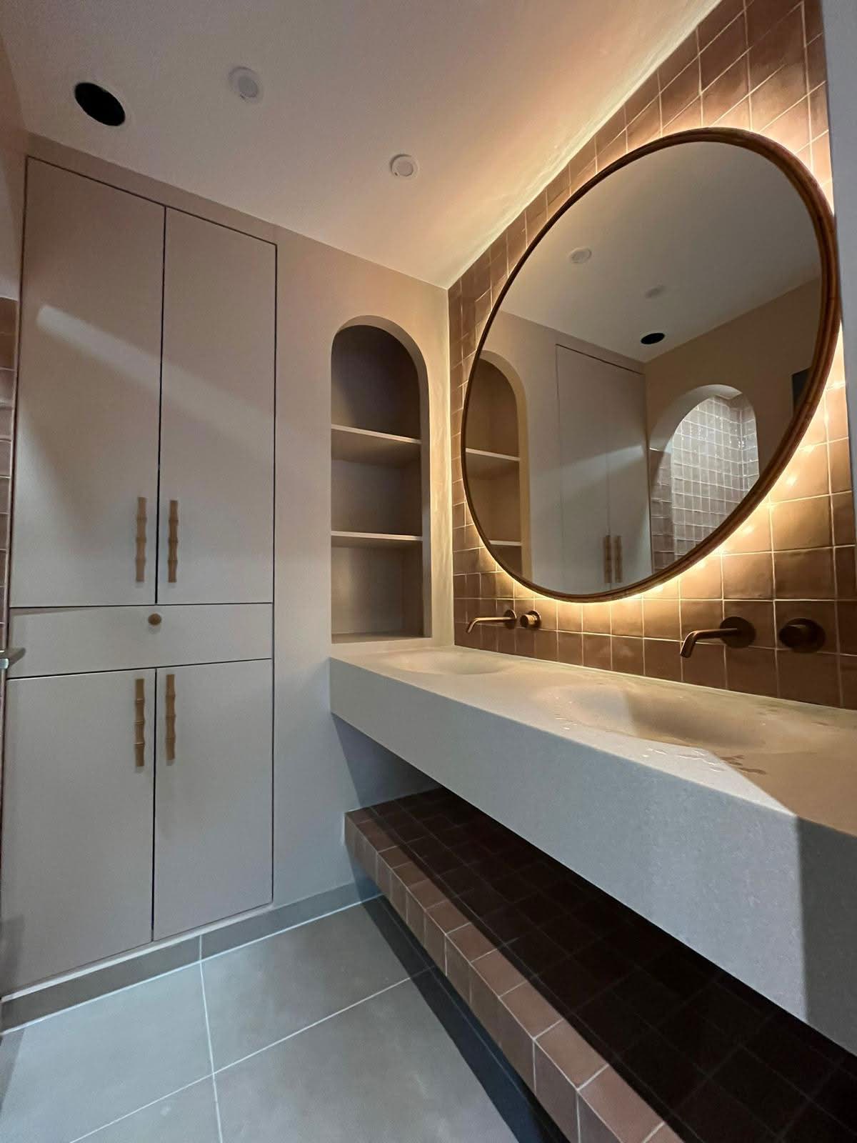 Salle d'eau haut de gamme avec double vasque suspendue et grand miroir rond rétroéclairé